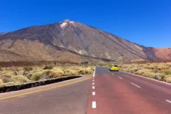 Foutparkeerders in Teide Nationaal Park - gele auto rijdt richting Teide op zonnige weg.